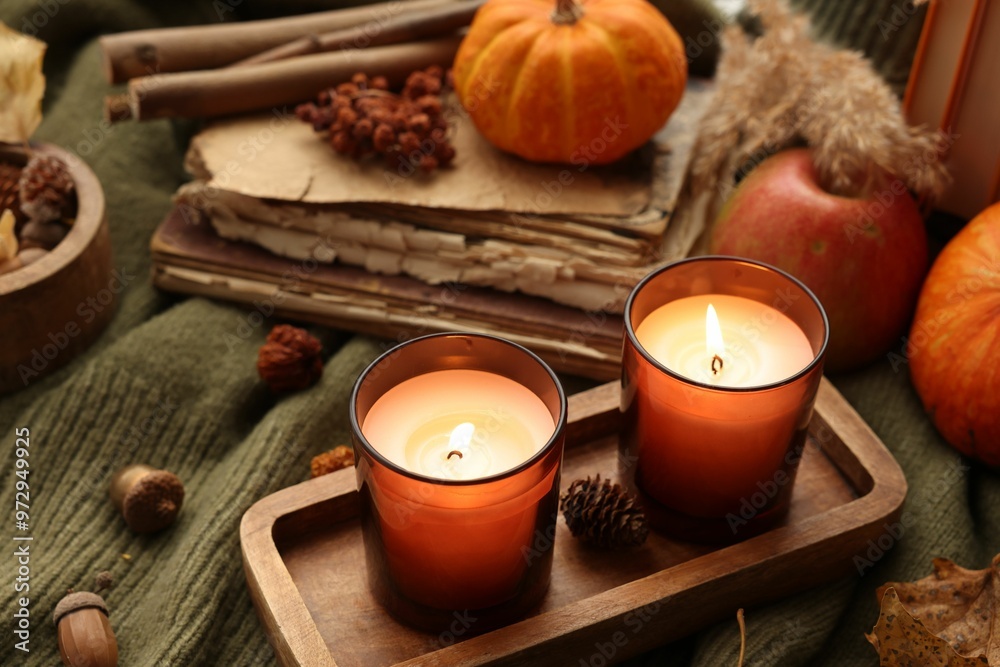 Burning candles, old books and autumn decor on green sweater Burning candles, old books and autumn decor on green sweater