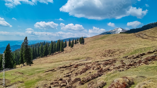 Scenic hiking trail over dry alpine meadows and rolling hills to snow-capped mountain peak Lenzmoarkogel, Gleinalpe, Lavantal Alps, Styria, Austria. Wanderlust in wilderness of Austrian Alps in spring photo