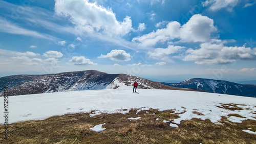 Hiker woman on scenic hiking trail over snow covered alpine meadows and rolling hills to snow-capped mountain peak Lenzmoarkogel, Gleinalpe, Lavantal Alps, Styria, Austria. Wanderlust in Austrian Alps photo