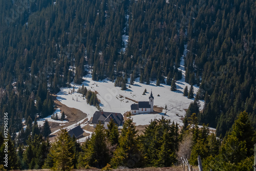 Picturesque church Maria Schnee on Gleinalpe, Lavantal Alps, Styria, Austria. Landmark nestled amidst mountainous landscape, snow-covered hills and dense pine forests. Tranquility in Austrian Alps photo