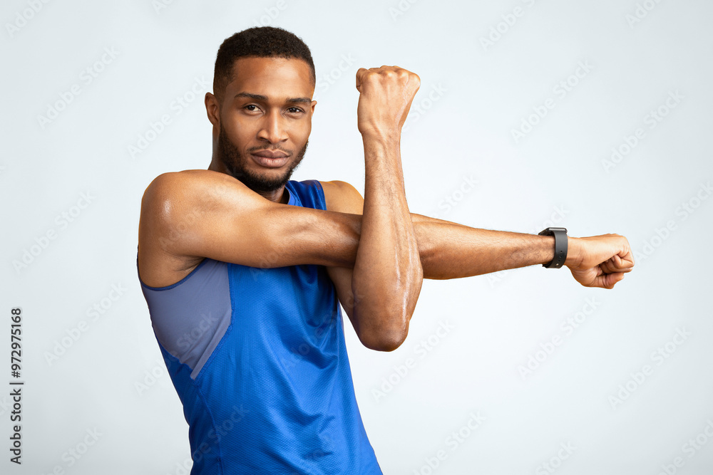 Warm Up. Muscular afro man stretching his arms and shoulders before gym workout over yellow studio wall, copyspace Warm Up. Muscular afro man stretching his arms and shoulders before gym workout over yellow studio wall, copyspace