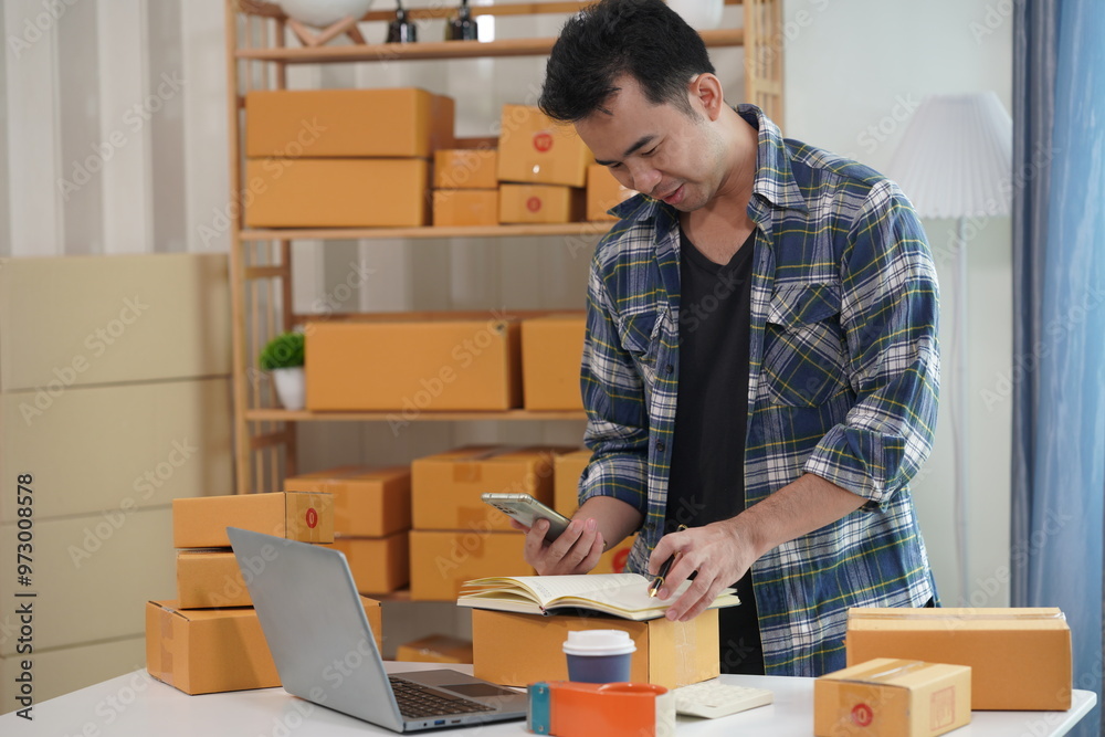 Small business owner starting up using smartphone and writing address on package box to send to customer. Concept of businessman doing ecommerce business on website and social media. Small business owner starting up using smartphone and writing address on package box to send to customer. Concept of businessman doing ecommerce business on website and social media.