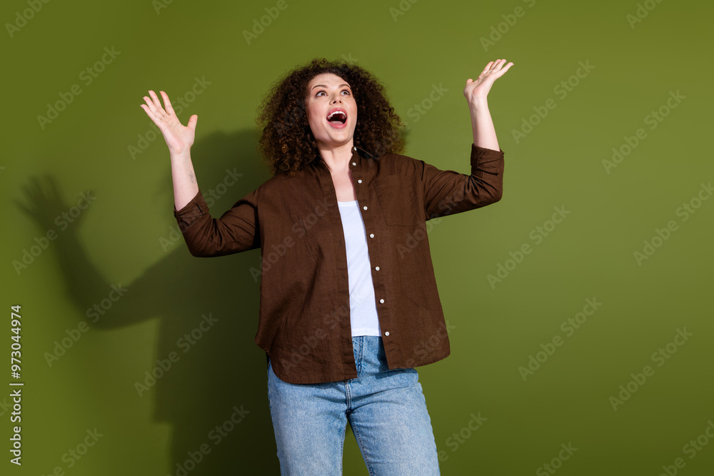 Portrait of nice young girl raise arms look up empty space wear brown shirt isolated on khaki color background Portrait of nice young girl raise arms look up empty space wear brown shirt isolated on khaki color background