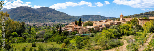 Panoramic view over the quaint village Biniaraix, framed by the lush valley of Sóller and Serra de Tramuntana mountains on a sunny day, ideal for promoting Mallorca as a tranquil travel destination.