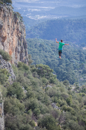 A tightrope walker walks along a cable stretched over a canyon.