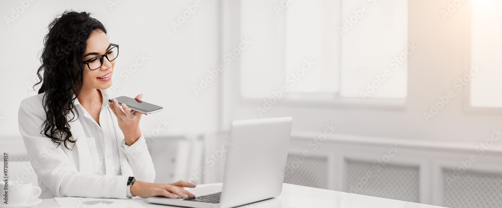 Voice Search. Smiling latin woman using smart phone voice recognition to send message at workplace, copyspace Voice Search. Smiling latin woman using smart phone voice recognition to send message at workplace, copyspace