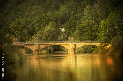 Steinbogenbrücke vor Wald an Hügel mit Wohnhaus von  Morgensonne beleuchtet