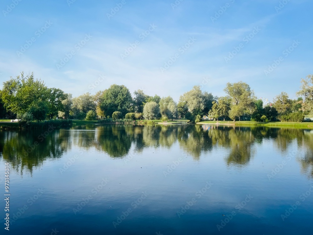 Trees reflection on the lake surface, blue lake in the park, summertime Trees reflection on the lake surface, blue lake in the park, summertime