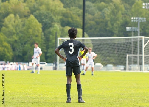 Black kid plays soccer against white kids.