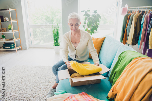 Photo of charming woman dressed white cardigan putting clothes in cardboard box moving apartment indoors photo