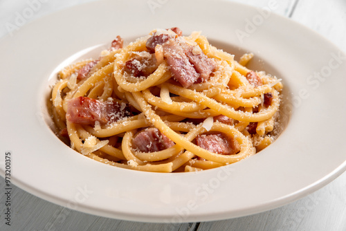 Primo piano di deliziosi bucatini alla gricia, ricetta tipica della cucina romana di pasta con guanciale, pecorino e pepe nero, cibo italiano  photo