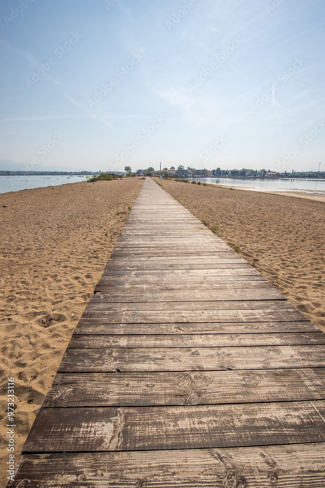A beach surrounded by the sea on both sides. In the middle a wooden footbridge runs along the sandy beach. Natural spectacle of a Mediterranean landscape, Plaža Ždrijac, Nin, Zadar, Dalmatia, Croatia A beach surrounded by the sea on both sides. In the middle a wooden footbridge runs along the sandy beach. Natural spectacle of a Mediterranean landscape, Plaža Ždrijac, Nin, Zadar, Dalmatia, Croatia