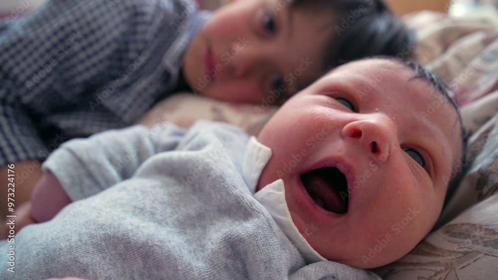 Older brother lying next to newborn sibling, both sharing a quiet and close moment, with the brother gently holding the baby’s hand, illustrating the warmth and bond between siblings Older brother lying next to newborn sibling, both sharing a quiet and close moment, with the brother gently holding the baby’s hand, illustrating the warmth and bond between siblings