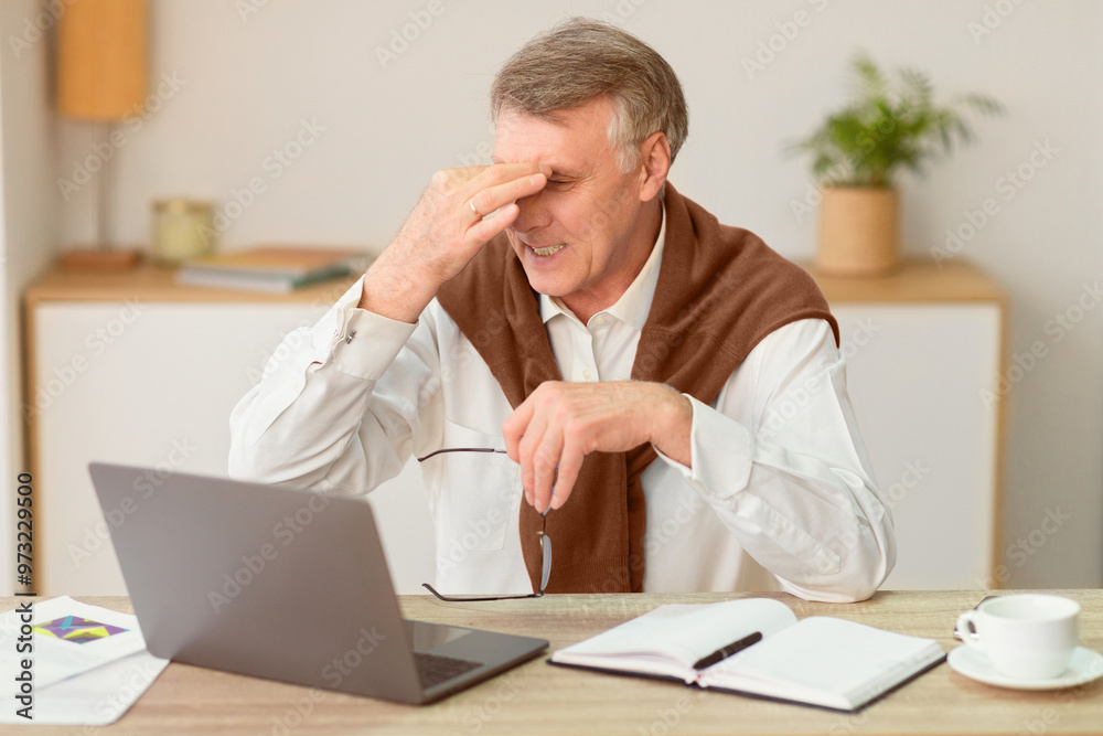 Eyestrain In Old Age. Senior Man Massaging Aching Eyes Holding Eyeglasses Working On Laptop Computer In Modern Office. Selective Focus Eyestrain In Old Age. Senior Man Massaging Aching Eyes Holding Eyeglasses Working On Laptop Computer In Modern Office. Selective Focus
