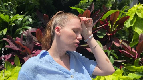Young woman feeling bad, suffering from sunstroke in tropical park at summer