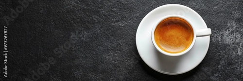 A white coffee cup filled with rich espresso sits on a white saucer against a dark gray background