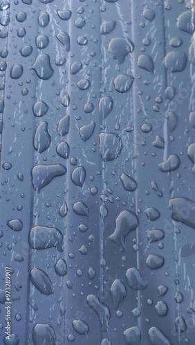 Gros plan d'une surface de tôle bleu foncé, avec macrophotographie sur flaque d'eau répandu, après passage de pluie, eau restant sur place, en équilibre, en cours de sèchement, beauté artistique photo