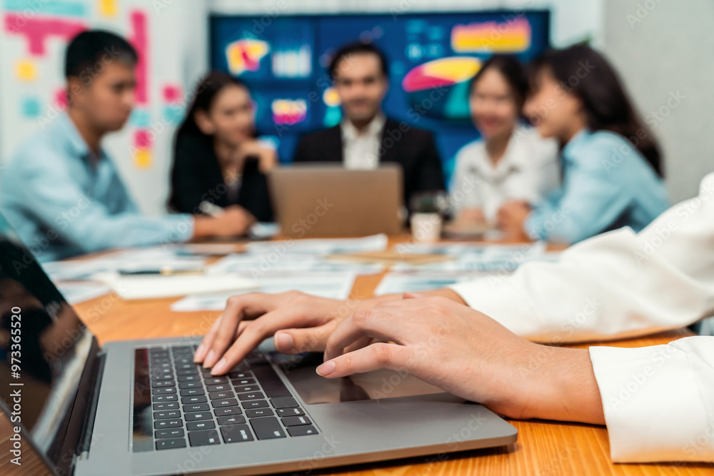 Closeup hand typing keyboard laptop with blurred background of business people using laptop to analyze financial data or data analysis display on screen background. Meticulous