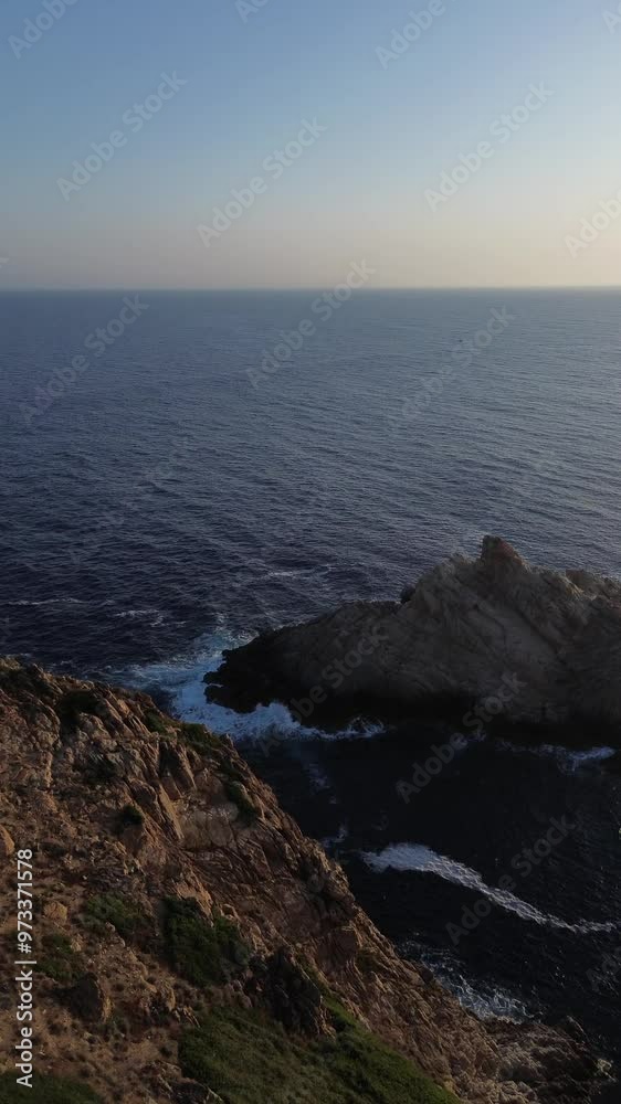 Blick nach unten auf die Wellen des Mittelmeers, die gegen einen Felsen der Küste Korsikas schlagen Blick nach unten auf die Wellen des Mittelmeers, die gegen einen Felsen der Küste Korsikas schlagen