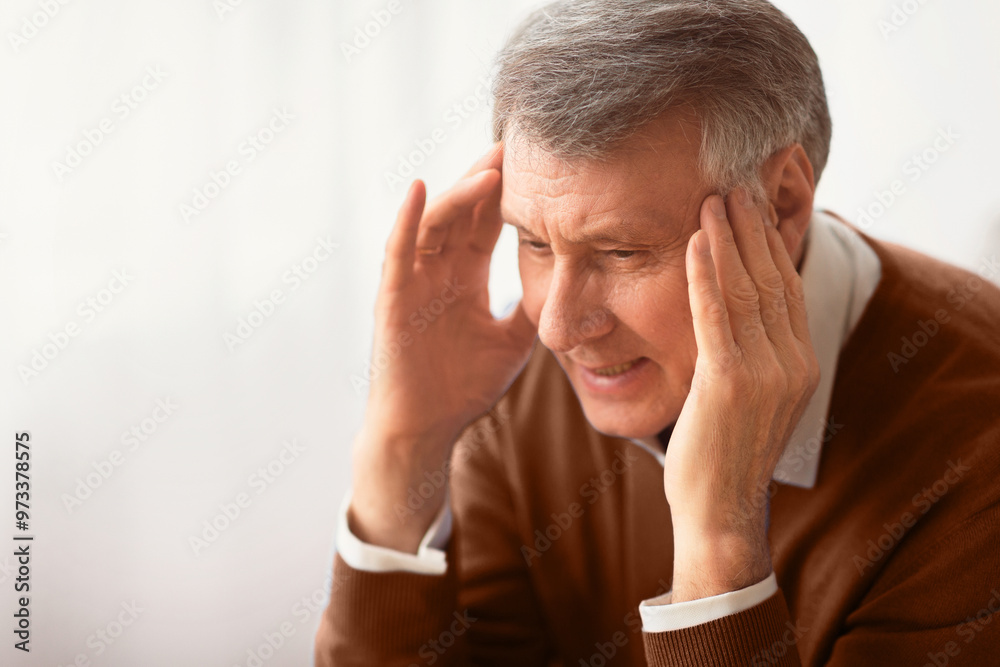 Fototapeta premium Migraine. Elderly Gentleman Having Headache Massaging Temples Sitting Against Window Indoor. Selective Focus