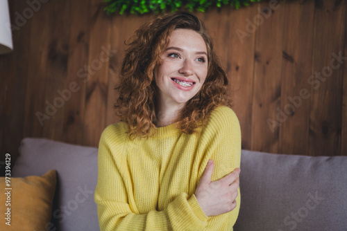 Photo of attractive young female sit couch look empty space hugging self dressed yellow sweater cozy day light home interior living room