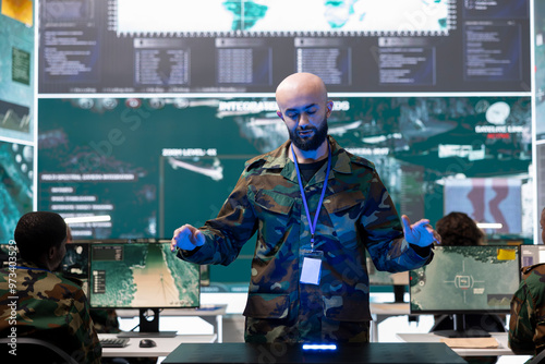 Military personnel studying a projection on hologram in command post, working on new defense operation plan. Soldier looking at real time CCTV satellite data on a holographic visualization.