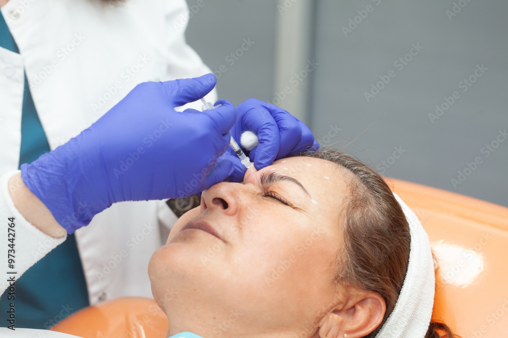 Dermatologist applying Botulinum toxin to a middle age female patient. Aesthetic medicine. Dermatologist applying Botulinum toxin to a middle age female patient. Aesthetic medicine.