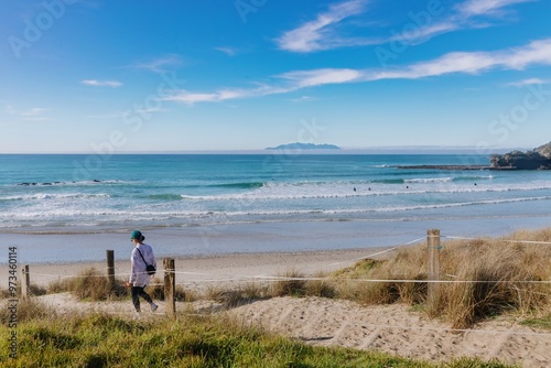 Woman walking onto the beach at Tawharanui, Warkworth, Auckland, New Zealand.