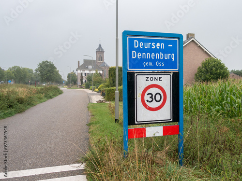 Place name sign of the village of Deursen-Dennenburg, municipality of Oss, the Netherlands, with speed limit sign for 30 km per hour photo