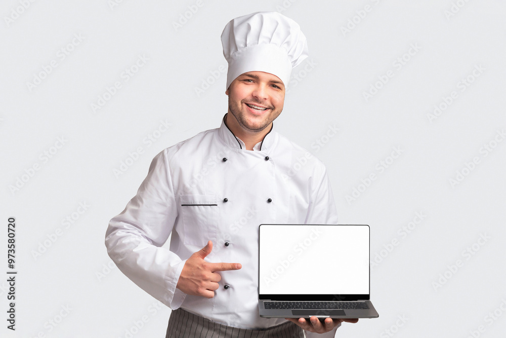 Chef Man Holding Laptop With Blank Screen Pointing Finger Standing Over White Studio Background. Cooking And Recipes Website. Panorama Chef Man Holding Laptop With Blank Screen Pointing Finger Standing Over White Studio Background. Cooking And Recipes Website. Panorama