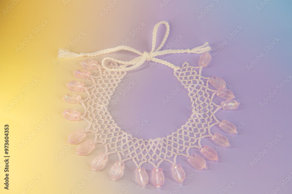 Light pink pendant ornate floral necklace made of beads on gradient background Light pink pendant ornate floral necklace made of beads on gradient background