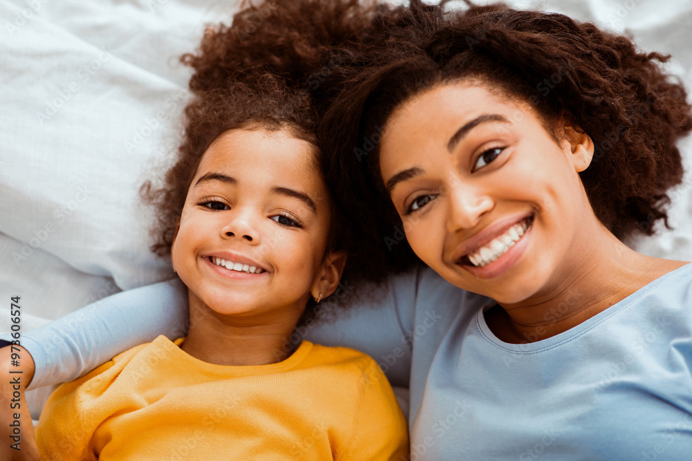 Bedtime Portrait. Afro Mother And Daughter Cuddling Lying In Bed In Bedroom Relaxing On Weekend. Selective Focus, Top View Bedtime Portrait. Afro Mother And Daughter Cuddling Lying In Bed In Bedroom Relaxing On Weekend. Selective Focus, Top View