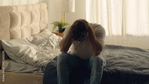 Caucasian man sitting on bed holding head grief pain crisis separation fatigue headache burnout bedroom guy male emotional stress tired exhaustion sadness anxiety distraught problems overworked loss