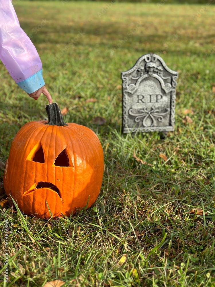 Obraz premium Child Touching Sad Jack-o'-Lantern Near Tombstone