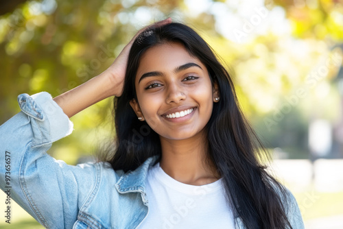 Indian woman in casual shirt smile arm on head at sunny park