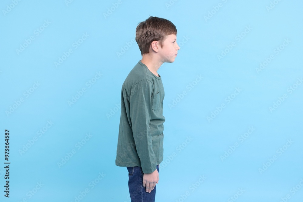 Boy with incorrect posture on light blue background Boy with incorrect posture on light blue background
