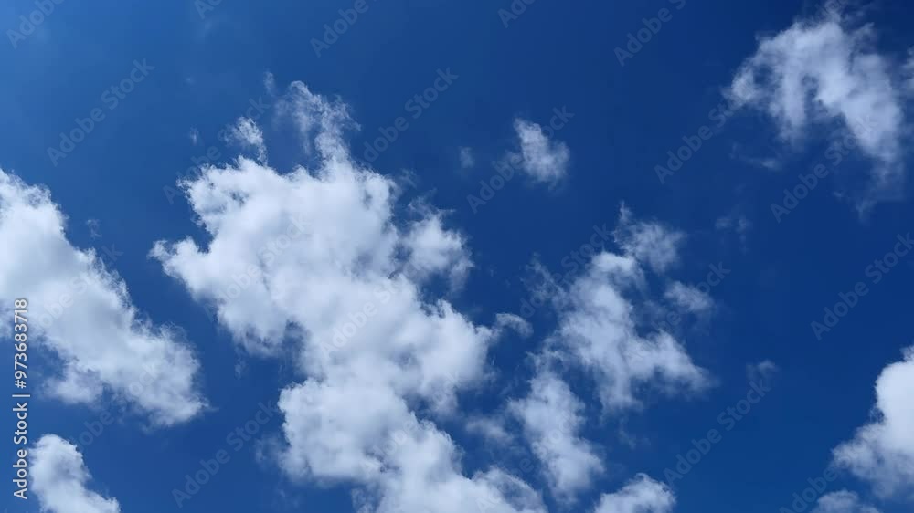 White fluffy clouds drift across a vibrant blue sky on a bright sunny day White fluffy clouds drift across a vibrant blue sky on a bright sunny day