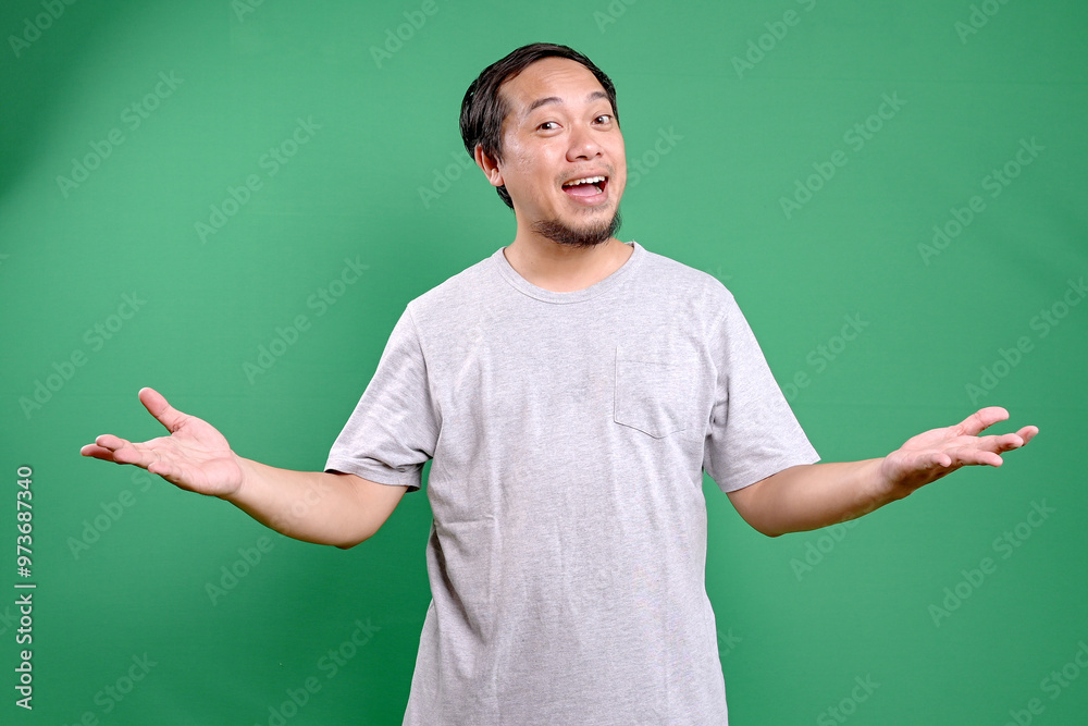 Asian man smiling with both hands opened doing welcoming pose isolated on green background Asian man smiling with both hands opened doing welcoming pose isolated on green background