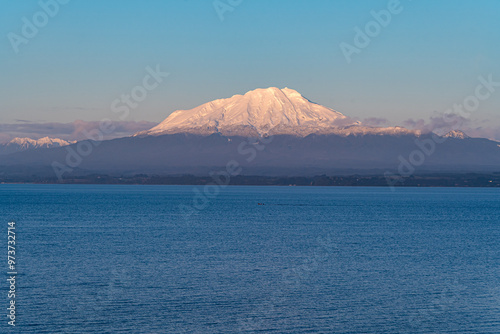 The snowy Calbuco volcano by lake Llanquihue seen from the other shore in the town of Llanquihue, Chilean Patagonia photo