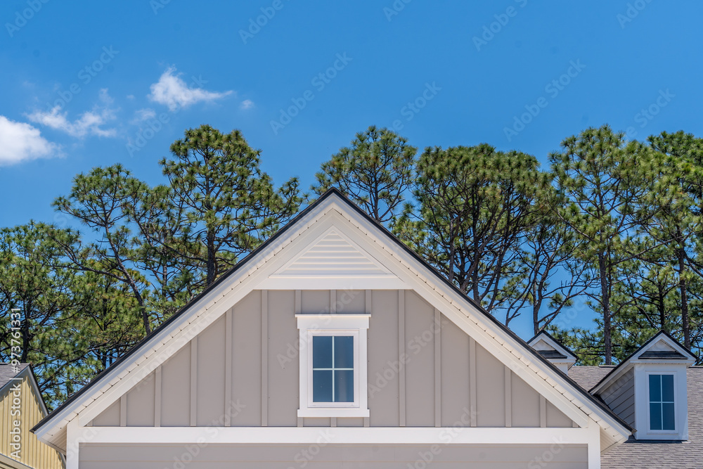 Gable with grey horizontal vinyl lap siding, double hung window with white frame, vinyl shutters on a pitched roof attic at a luxury American single family home neighborhood USA