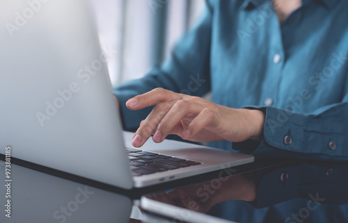 Woman hand typing on laptop computer, close up. Business woman working, surfing the internet on laptop with digital tablet on table at modern office, internet networking