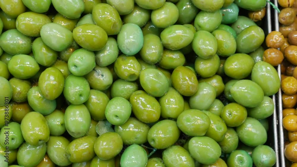 A vibrant selection of fresh green and brown olives elegantly displayed at a market stall A vibrant selection of fresh green and brown olives elegantly displayed at a market stall