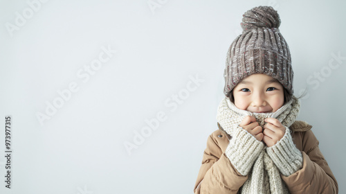 A cute and happy Asian girl dressing in grey winter clothes on a plain white background with copy space for text. photo