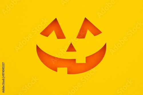 A simple orange jack-o'-lantern face cut out of yellow paper