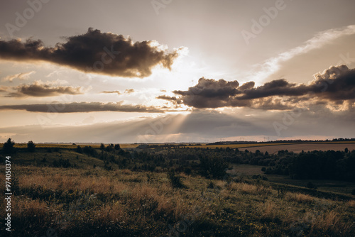 sunset landscape, valley with field grasses and flowers. cloudy sky photo