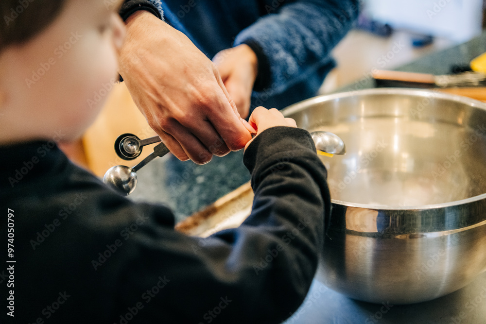 Close-up of a child and an adult measuring ingredients Close-up of a child and an adult measuring ingredients