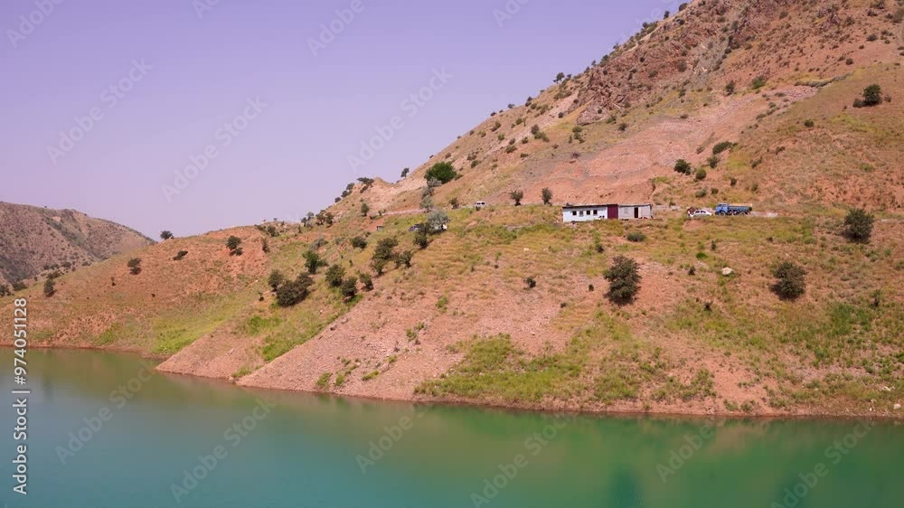 A mountain with a house on top of it and a body of water A mountain with a house on top of it and a body of water