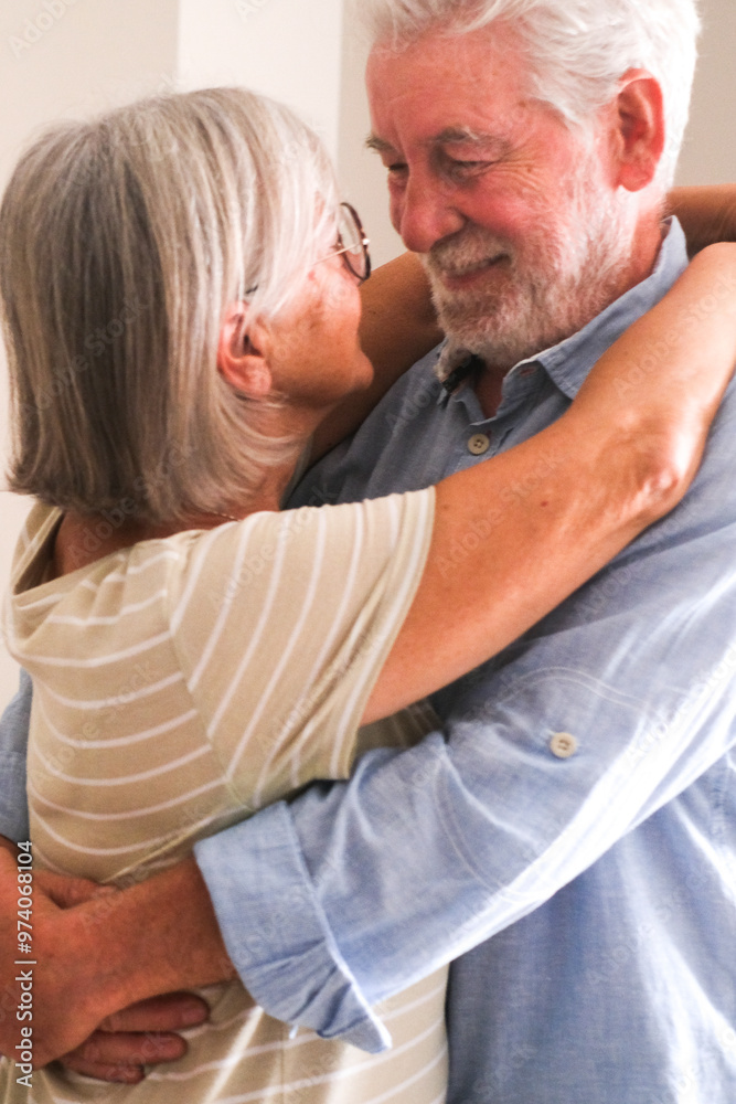 Close-up of an elderly couple happily embracing and celebrating their lifelong relationship at home. Both with joyful expressions, they look at each other, showcasing their love and health in Close-up of an elderly couple happily embracing and celebrating their lifelong relationship at home. Both with joyful expressions, they look at each other, showcasing their love and health in