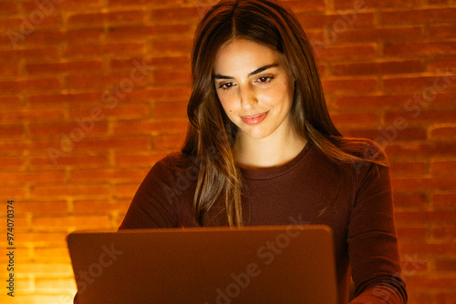 Professional woman working in the evening from her home office on a laptop. The scene captures the essence of modern freelance life, remote work, and digital professionals updating their online 