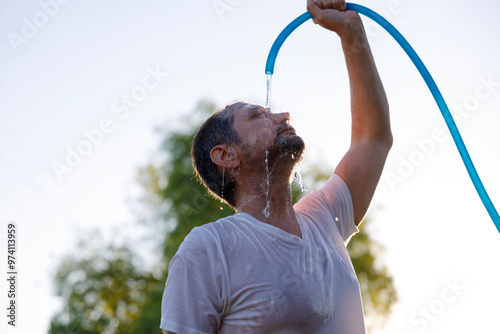 Young man cools down with cold water during the summer heat